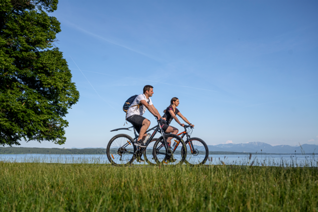 Zwei Radfahrer sind am See unterwegs.
