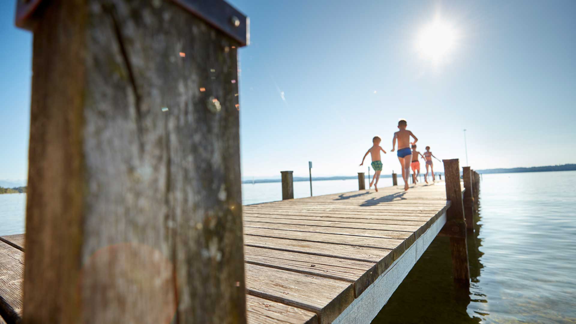 Die Kinder springen vom Steg aus ins Wasser